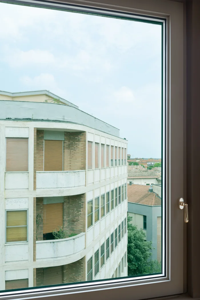 Accessori finestra - finestra aperta con maniglia in ottone e vista esterna su palazzina italiana
