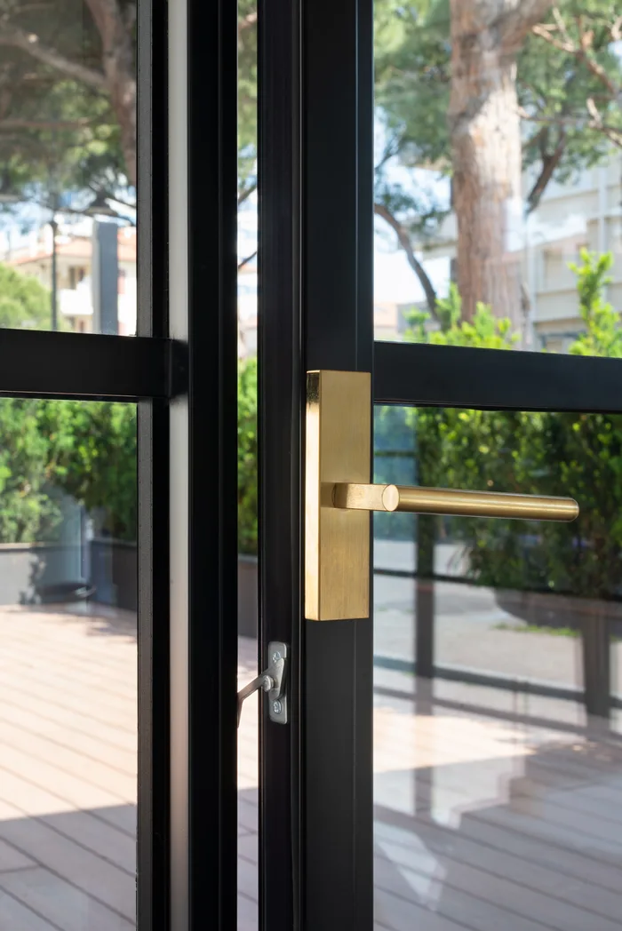 Accessori finestra - maniglia in ottone su serramento di pregio con telaio nero e vista sul giardino