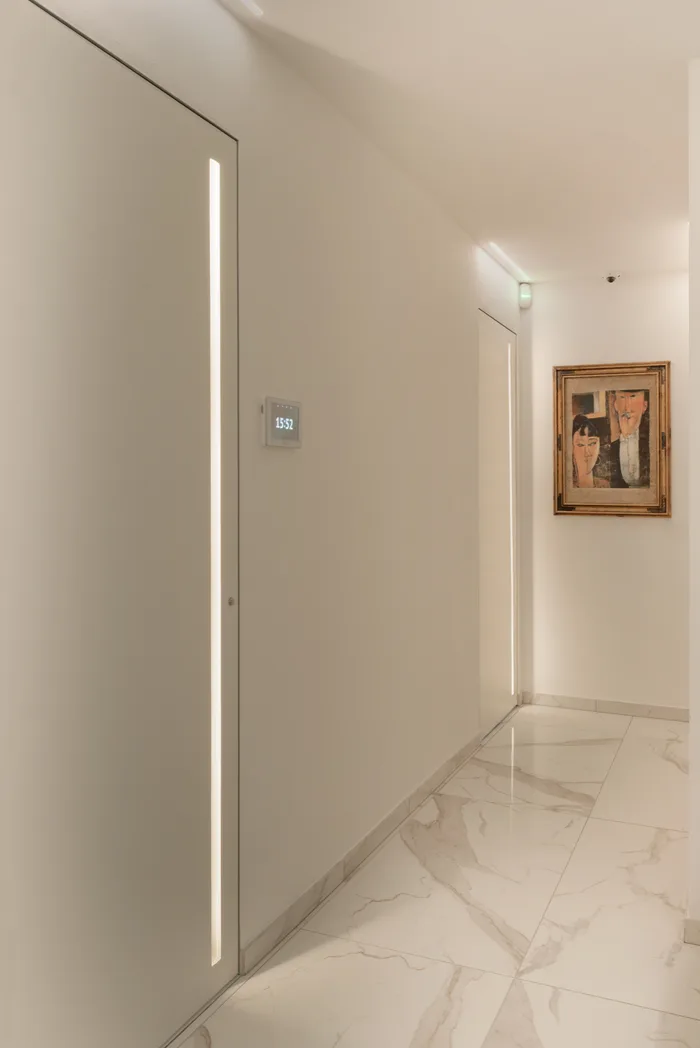 Porta interna bianca raso muro con illuminazione LED in corridoio di villa di lusso - esempio Lualdi installato da Bisacchi
