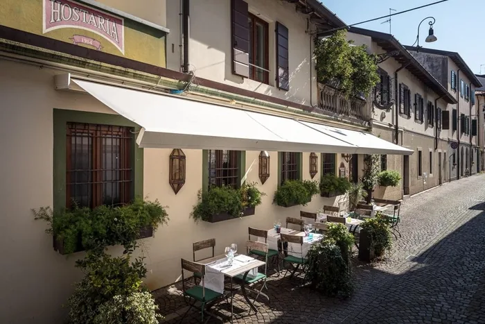 Tenda da sole a bracci bianca su un bar ristorante con tavolini all'aperto