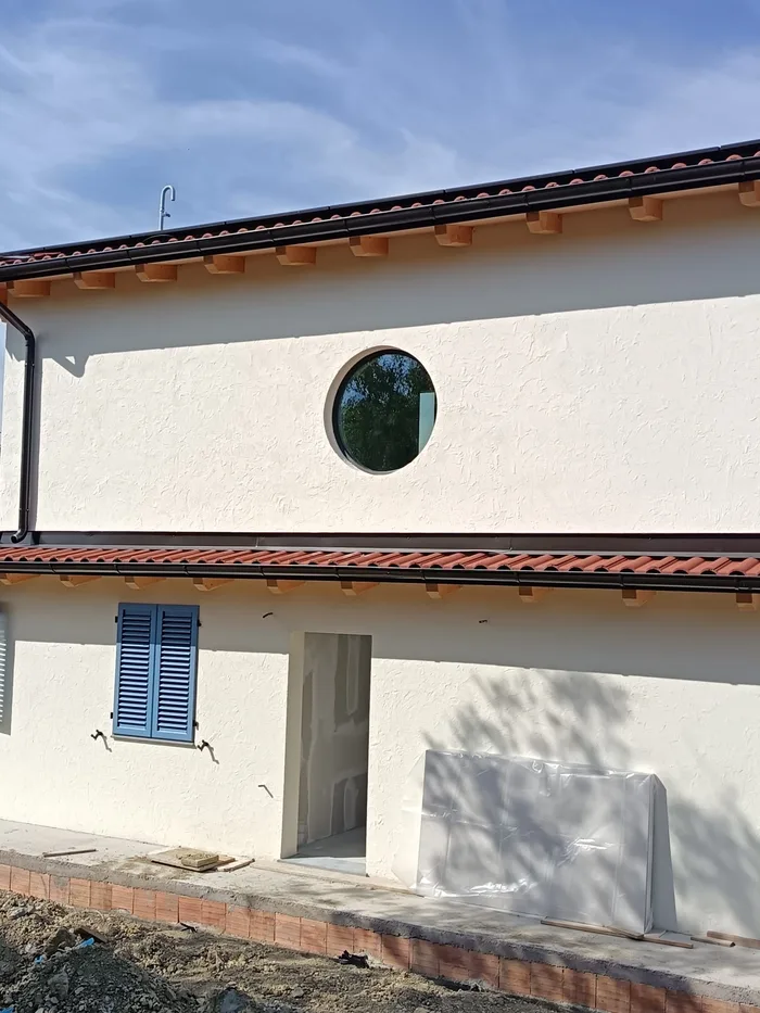 Infissi colorati blu: scuri azzurri su una facciata chiara con finestra rotonda