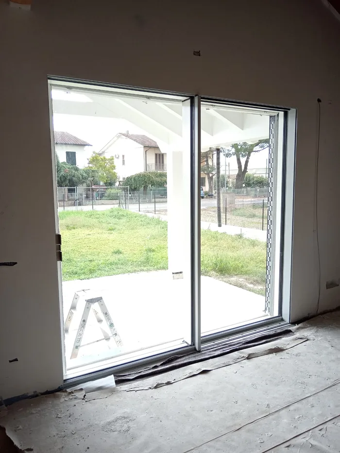 Infisso esterno bianco scorrevole in fase di posa in una villa moderna