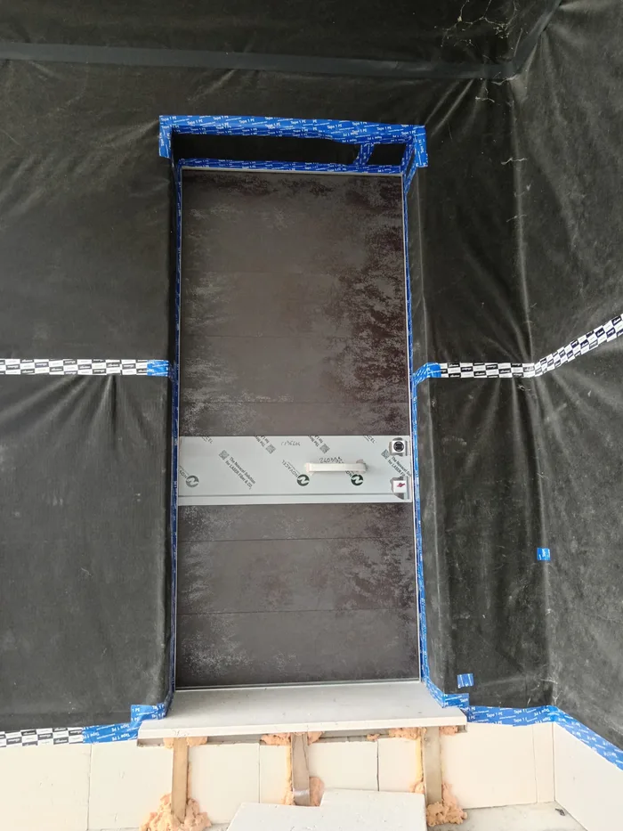 Posa di una porta blindata in alluminio in cantiere, protetta e con controtelaio nastrato