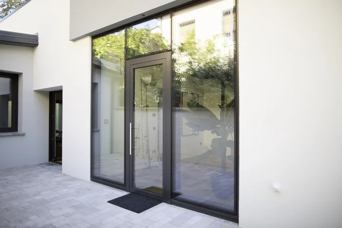 Porta blindata in alluminio vetrata minimal antracite con vetrate laterali su villa moderna