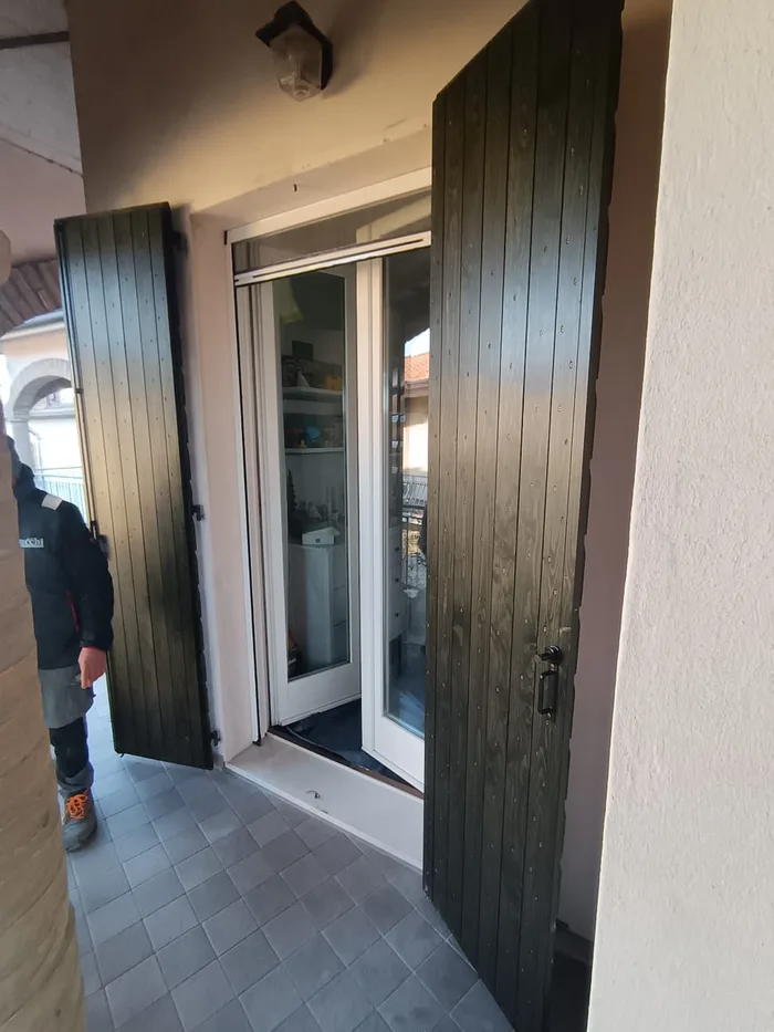 Scuri in legno verde scuro abbinati a porta finestra bianca