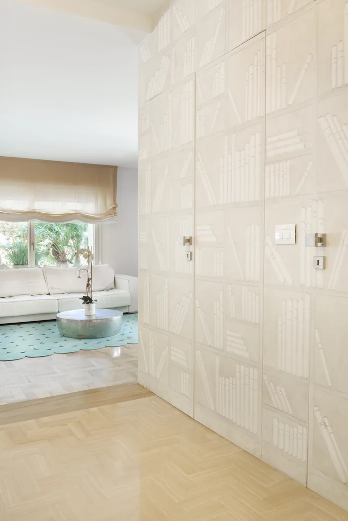 Parete di porte a scomparsa filomuro laccate con finitura decorativa in una villa