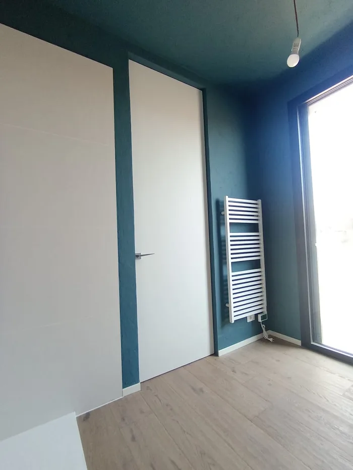 Porte senza controtelaio: porta filo muro bianca su parete color petrolio