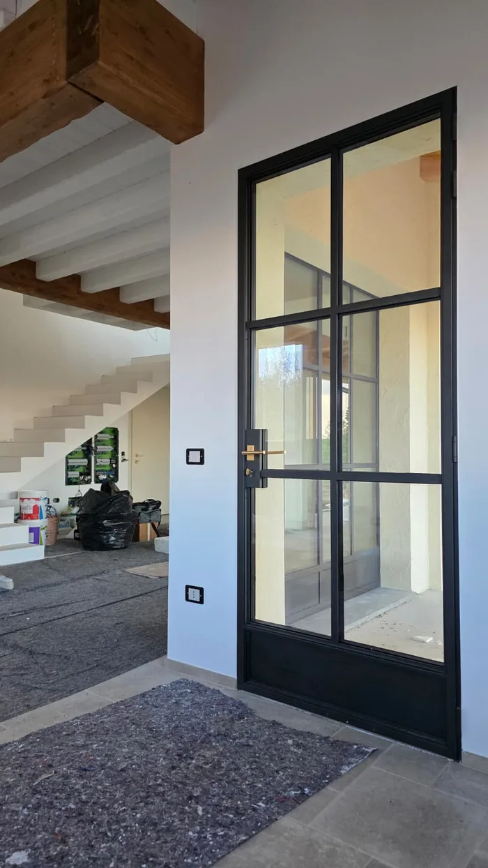 Porta d'ingresso di design in acciaio nero e vetro con maniglia in ottone