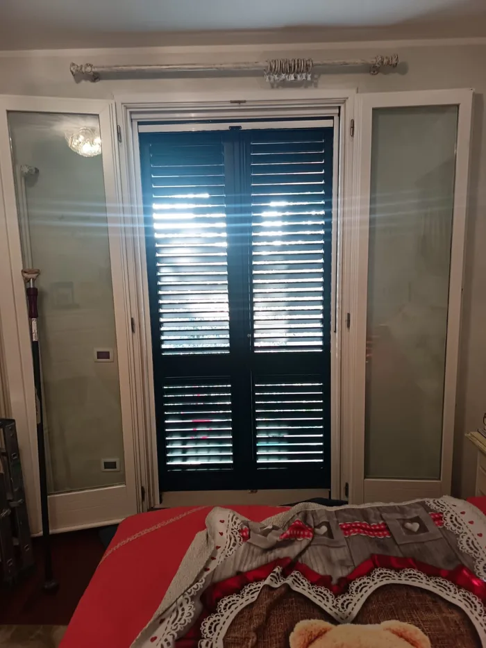 Scuri interni a lamelle su una porta-finestra in una camera classica