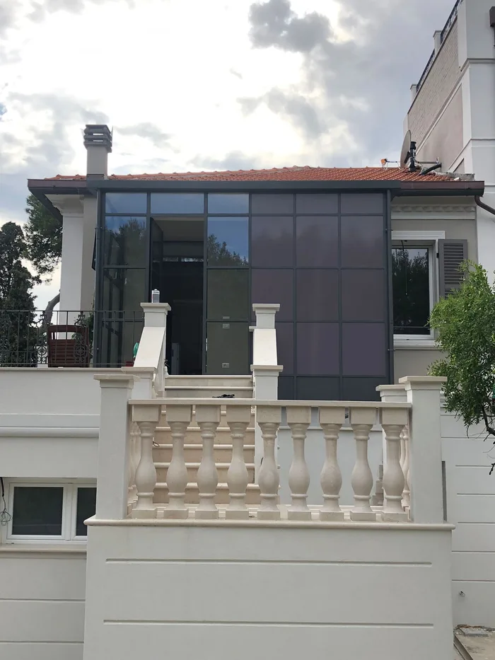 Verande mobili per terrazzi: veranda vetrata scura su terrazza di villa classica