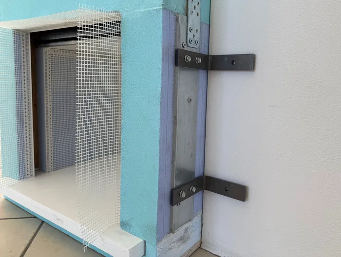 Ancoraggio antieffrazione di un serramento al muro con staffe metalliche, dettaglio di posa