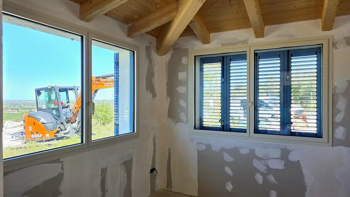 Finestre bianche in PVC appena posate in cantiere con scuri blu