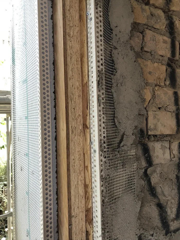 Sezione laterale del vano finestra con muratura in mattoni, isolante e rete
