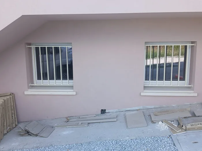 Grate antieffrazione: inferriate fisse bianche certificate su due finestre in cantiere
