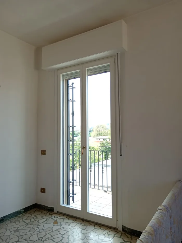 Inferriate apribili a scomparsa su una portafinestra bianca di un appartamento classico