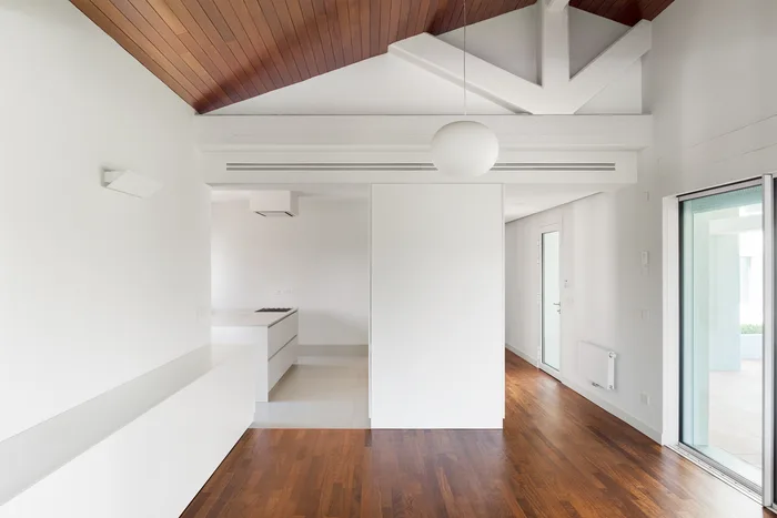 Infissi in PVC bianco curati in un soggiorno luminoso con tetto in legno