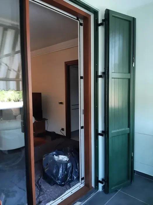 Posa di una persiana in alluminio verde su un ingresso con vetrata