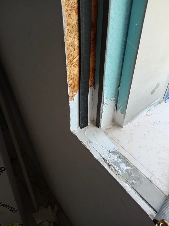Dettaglio della posa della soglia di un infisso bianco in cantiere