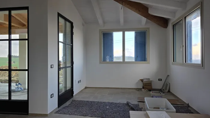Ristrutturare fienile costi: cantiere con travi a vista, portafinestra in ferro e finestre con scuri