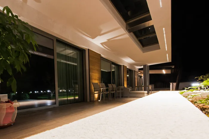 Grandi scorrevoli in alluminio antracite di alta qualità su una villa moderna di lusso illuminata la sera