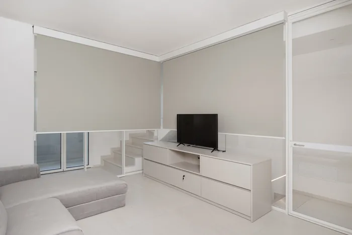 Soggiorno minimal con scorrevole bianco e tende a rullo