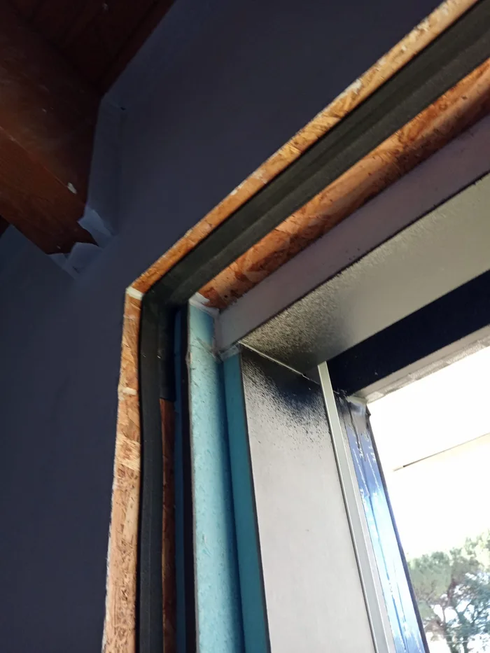 Dettaglio dell'angolo di un infisso in cantiere con nastri e strati di tenuta