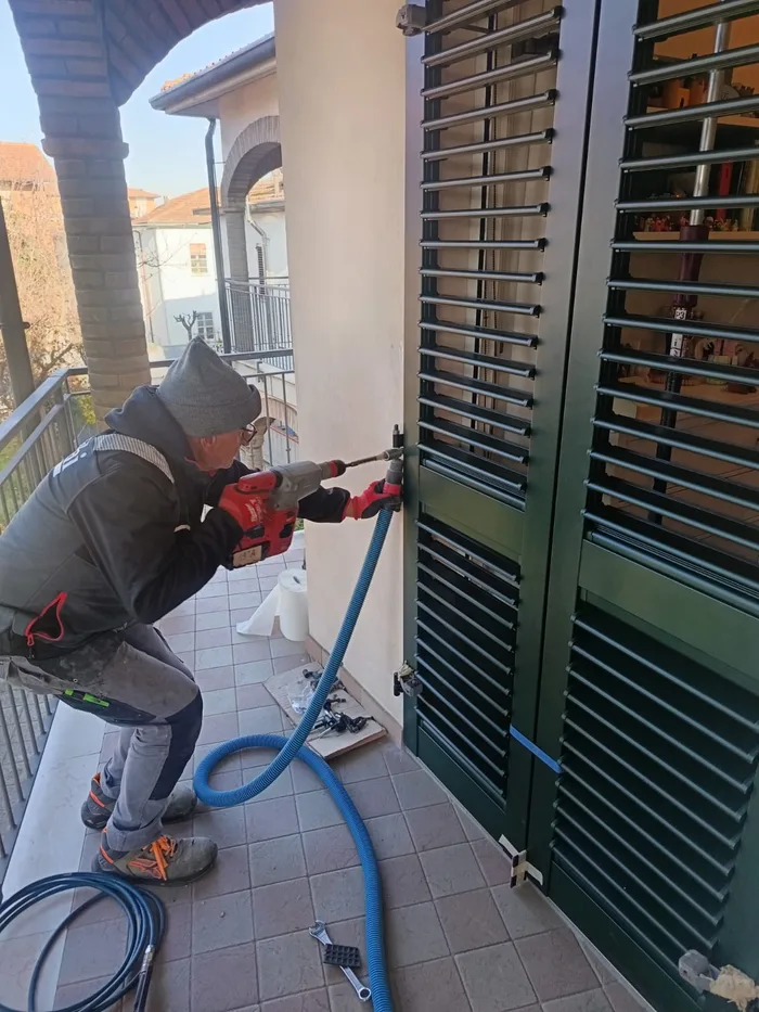 Posatore Bisacchi al lavoro sulla posa di scuri verdi su un balcone classico