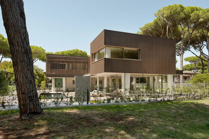 Villa moderna con rivestimento in doghe di legno e serramenti color legno tra i pini