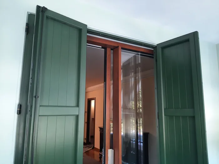 Serramento color legno con scuri verdi visto dall'interno di un appartamento