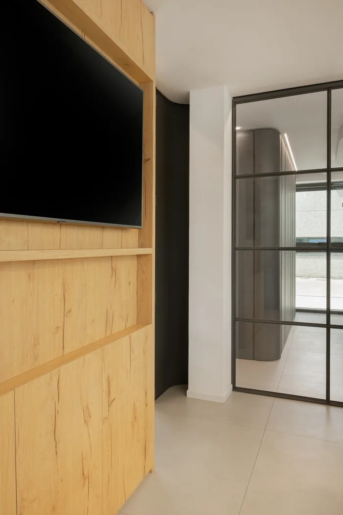 Interno con parete in legno e vetrata antracite dopo la sostituzione dei serramenti