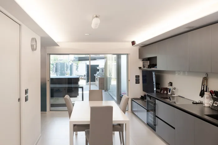 Cucina e zona pranzo con infissi in PVC bianco e portafinestra sul giardino
