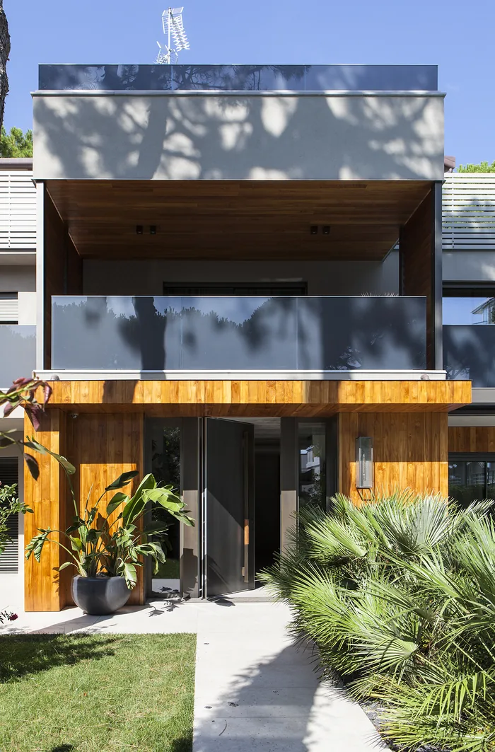 Villa moderna con infissi antracite e rivestimento in legno vista dal giardino