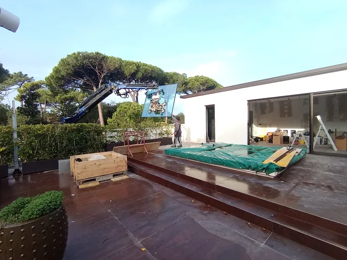 Lastra di vetro sollevata con gru e ventose durante la posa in cantiere su terrazzo