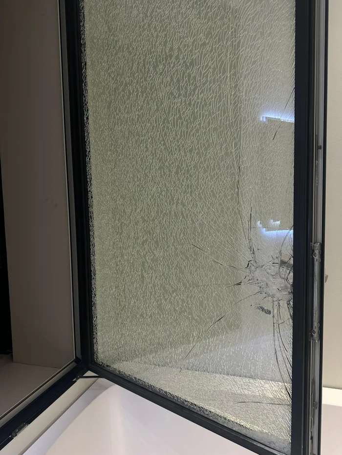Vetro di una porta danneggiato da un urto con crepe visibili sulla lastra